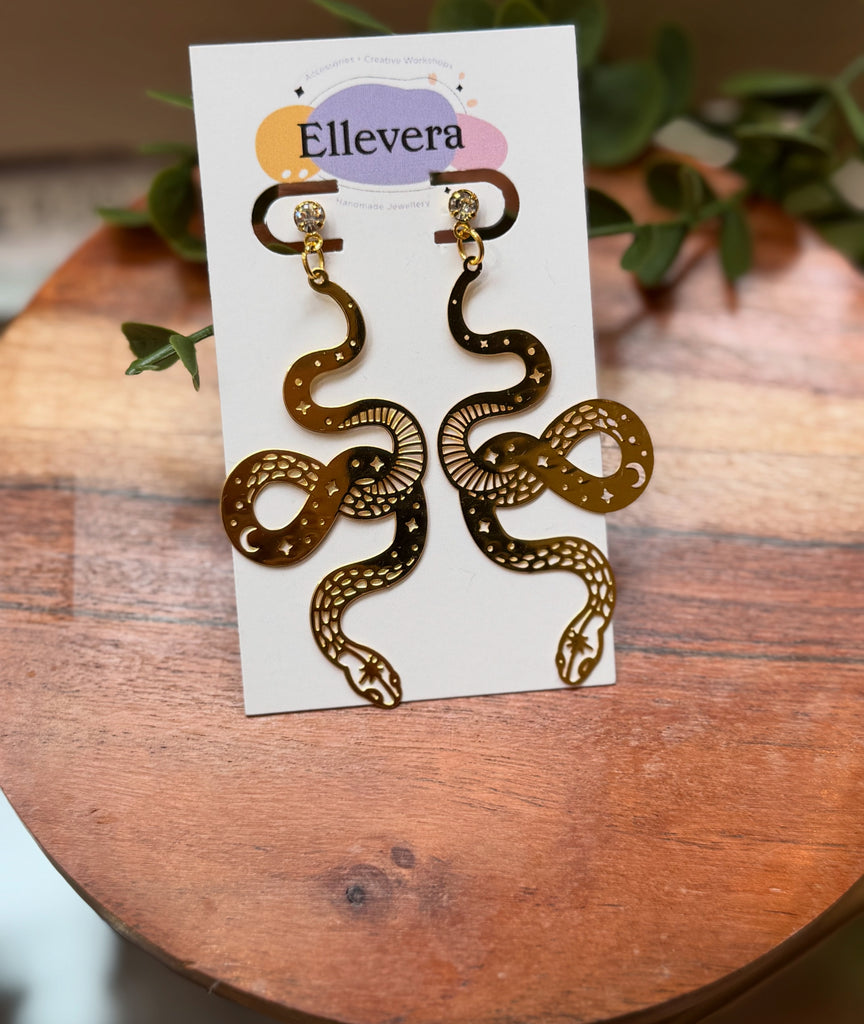 Large gold snake statement earrings with celestial cut-outs.