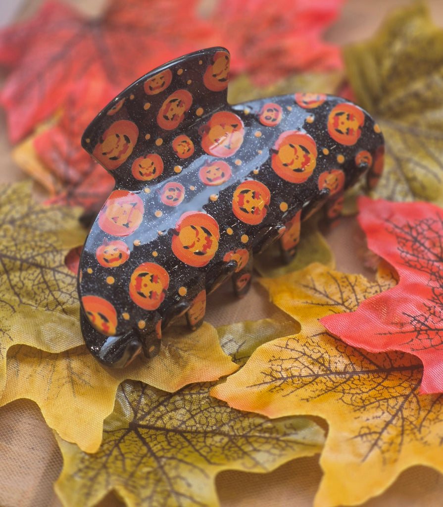 Black glitter claw clip with bright orange jack-o’-lantern pumpkin design