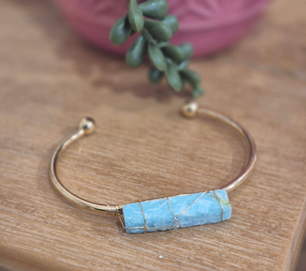 Gold open cuff bracelet featuring a raw turquoise amazonite crystal wrapped in gold wire.