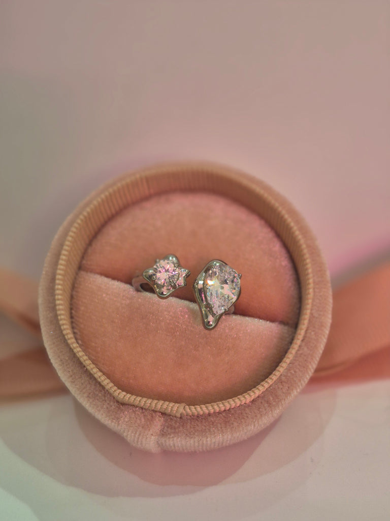 Silver adjustable ring with two clear sparkling stones displayed in a pink velvet ring box.