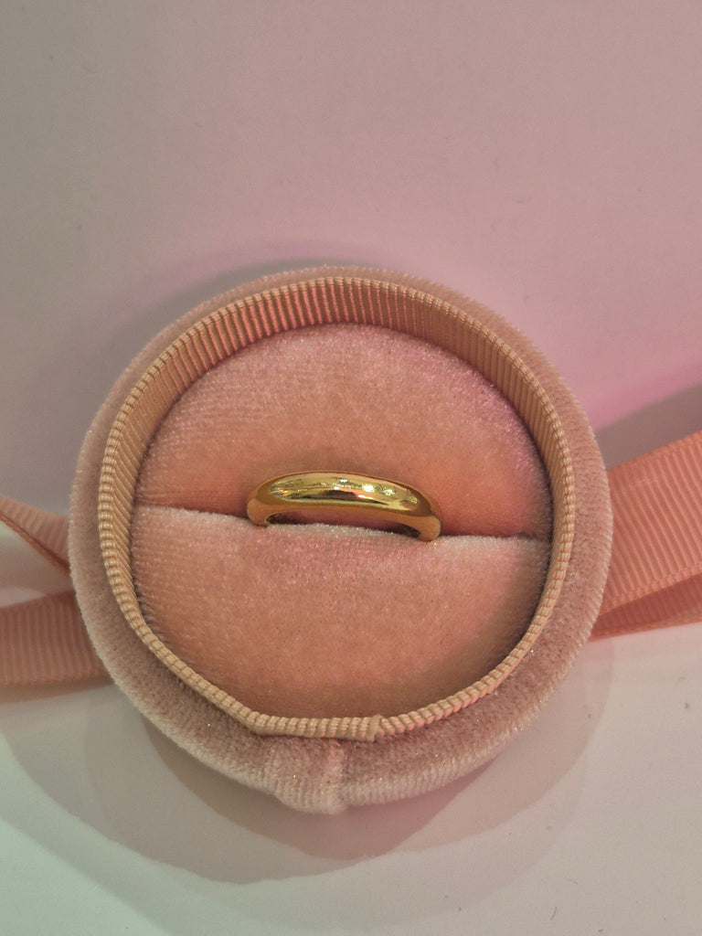 Gold dome ring displayed in a pink velvet ring box with a ribbon accent.