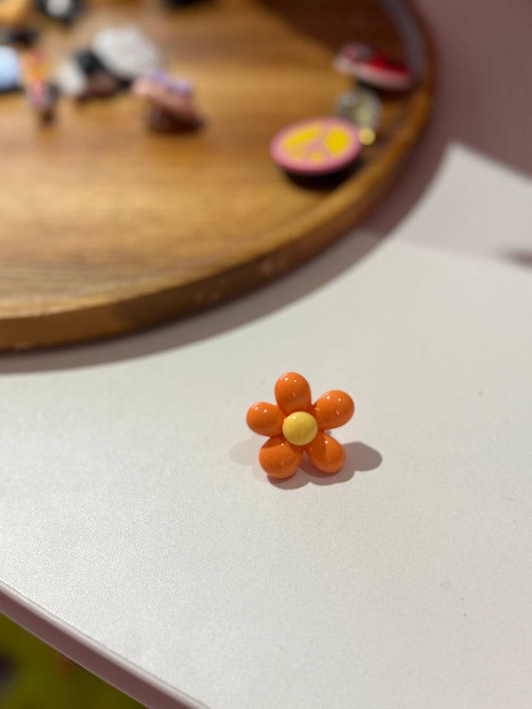 Orange flower Croc charm with six petals and yellow centre.