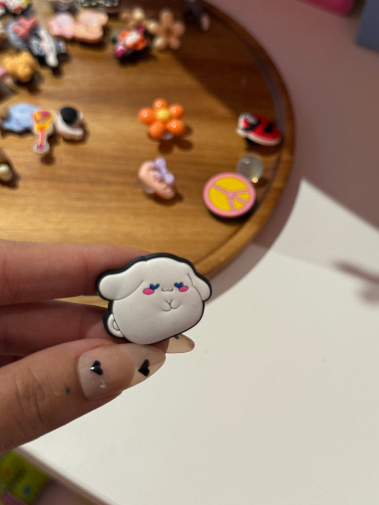 Close-up of a cute sheep face Croc charm with pink cheeks.