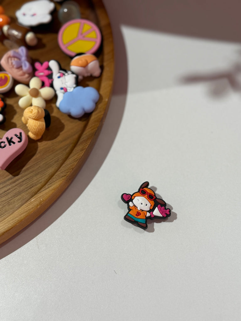 Bunny Croc charm wearing orange hoodie and holding pink pom poms.