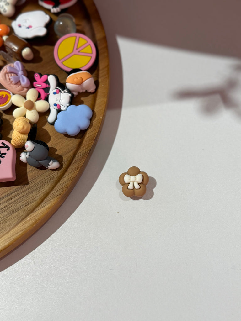 Brown flower Croc charm with white bow centre.