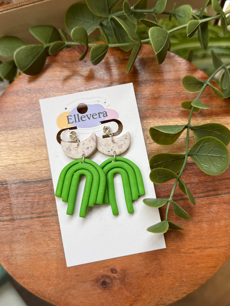 Polymer clay earrings with speckled crescent moons and bold green rainbow shapes.