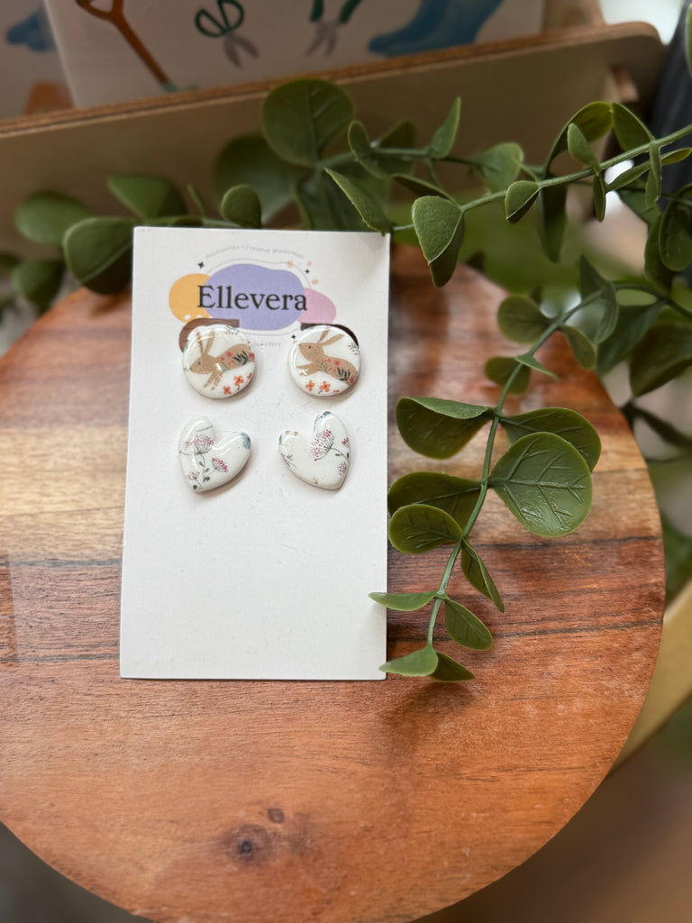 Polymer clay stud earrings – one bunny-print round pair and one floral heart pair on Ellevera backing card.