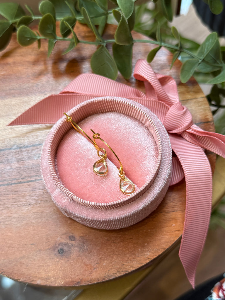 Gold hoop earrings with dangling teardrop crystal charms.