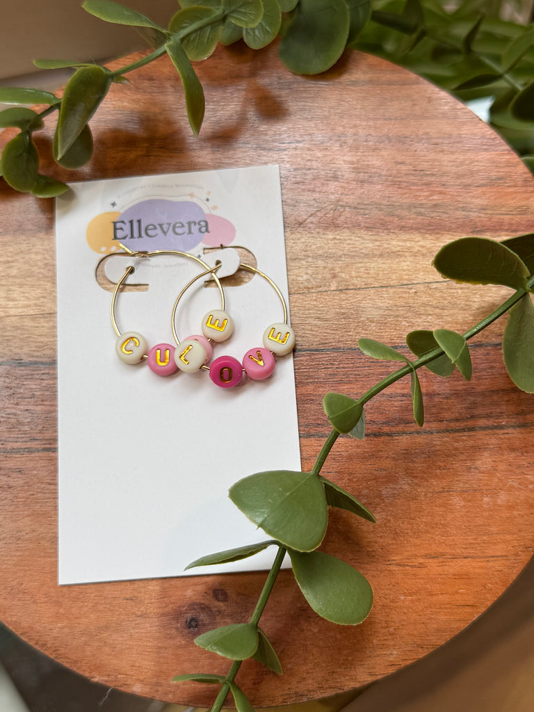 Gold hoop earrings with colourful beads spelling CUTE and LOVE.