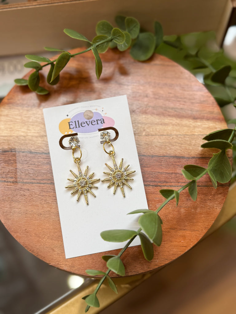 Gold starburst drop earrings with crystal centre.