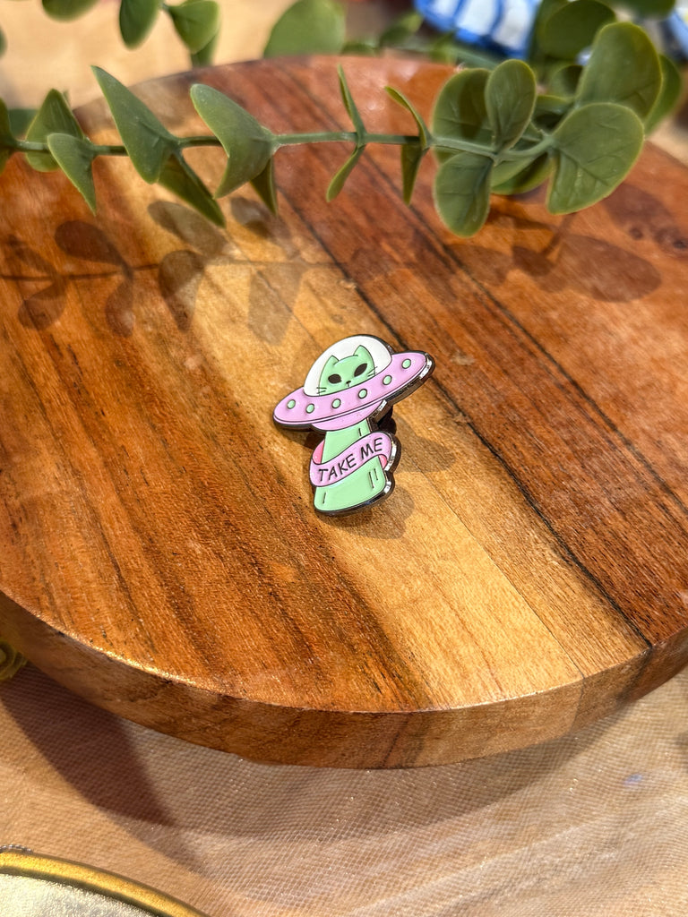 Alien enamel pin – green alien in pink UFO with words Take Me