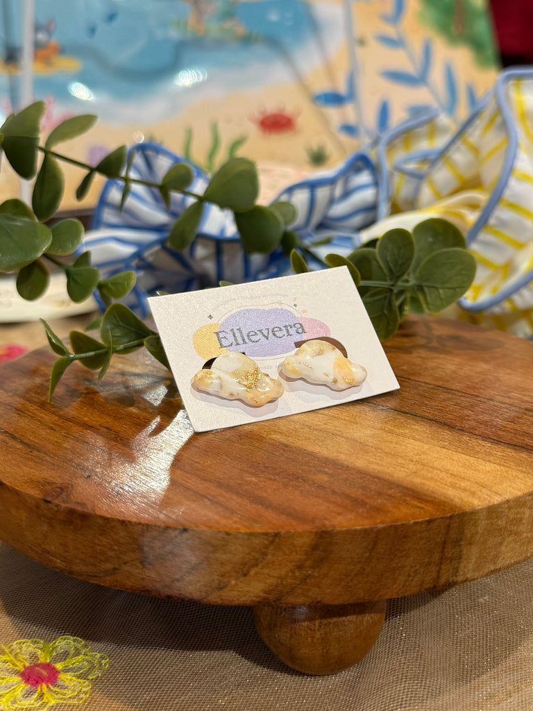 White cloud-shaped earrings with gold shimmer on Ellevera backing card.