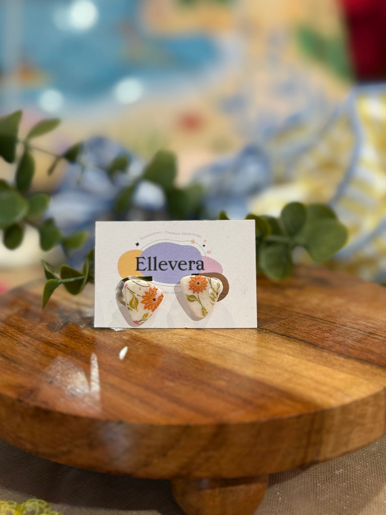 Triangle-shaped polymer clay earrings with orange floral design on Ellevera backing card.