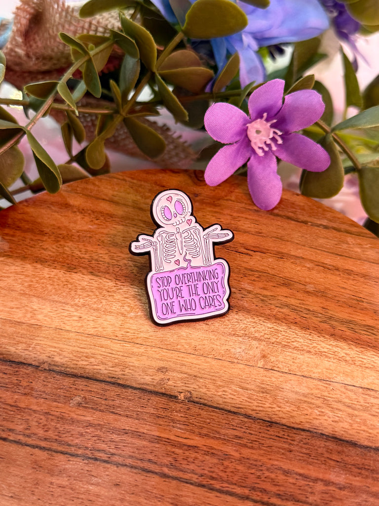 Enamel pin with skeleton and text “Stop Overthinking, You’re The Only One Who Cares.”
