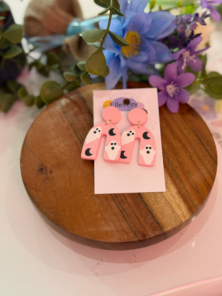 Pink statement earrings with ghost and moon designs.
