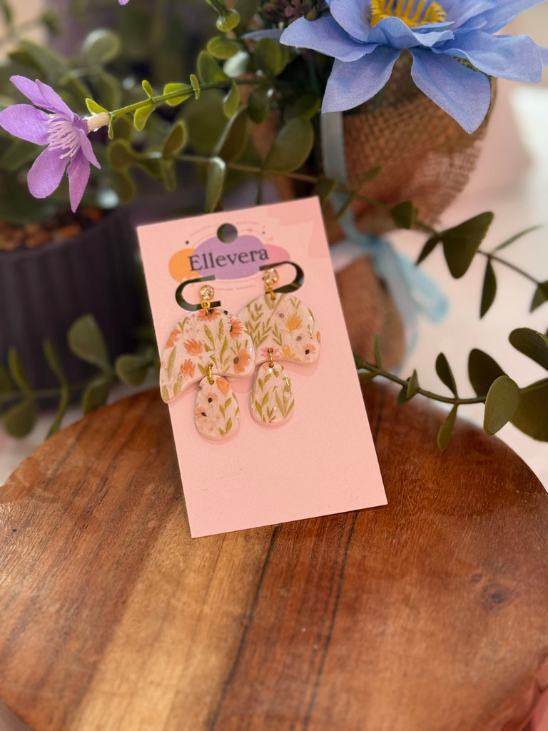 Pastel floral drop earrings with delicate wildflower-inspired design in soft pink and green tones, displayed on Ellevera backing card
