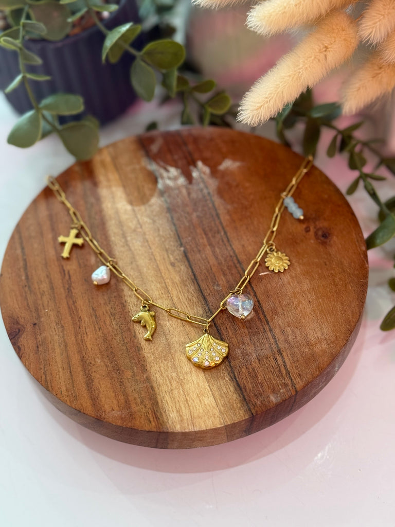 Golden Ocean Charms Necklace with seashell, dolphin, flower, and crystal heart pendants on a gold chain.