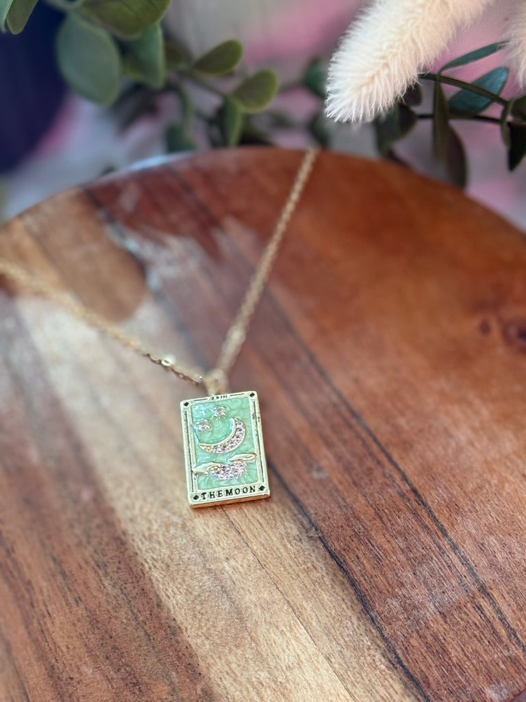 The Moon Tarot Necklace in gold with green and pink celestial tarot card design.
