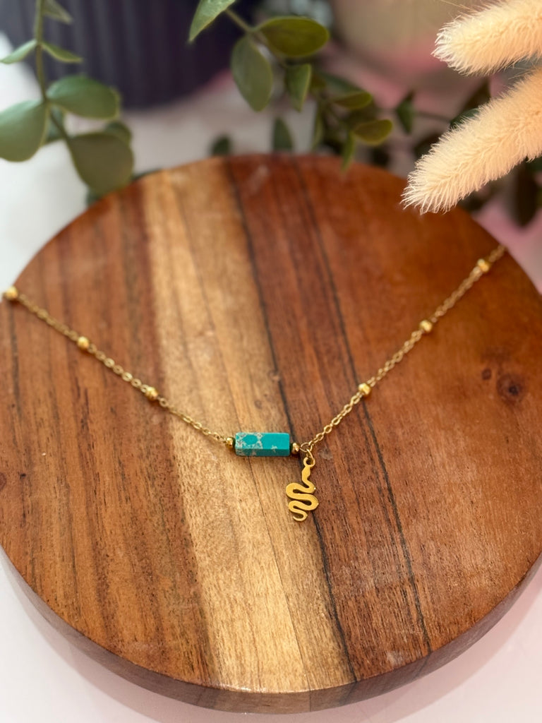 Gold necklace with turquoise stone and golden snake charm.