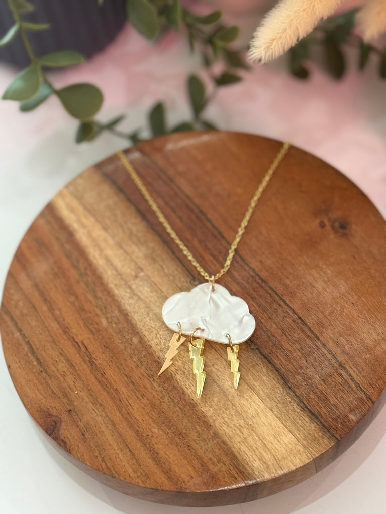Storm Cloud Necklace with white clay cloud and dangling gold lightning bolts on a gold chain.
