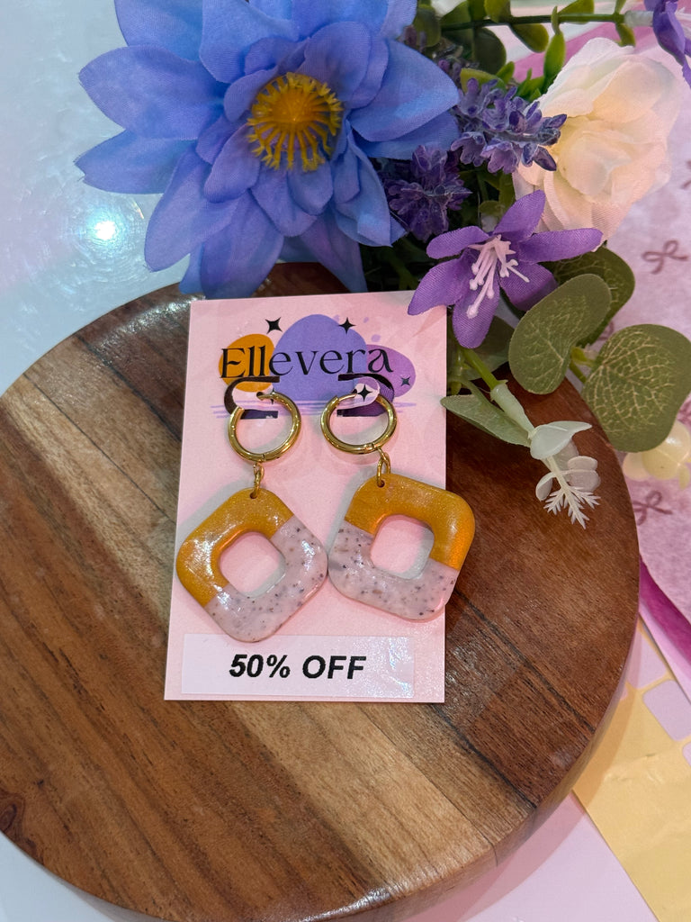 Mustard yellow and speckled white square polymer clay earrings on Ellevera backing card.