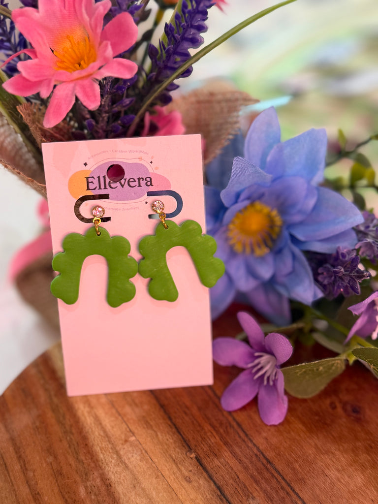 Handmade green abstract polymer clay earrings with wavy arch design and sparkling stud tops on Ellevera backing card.