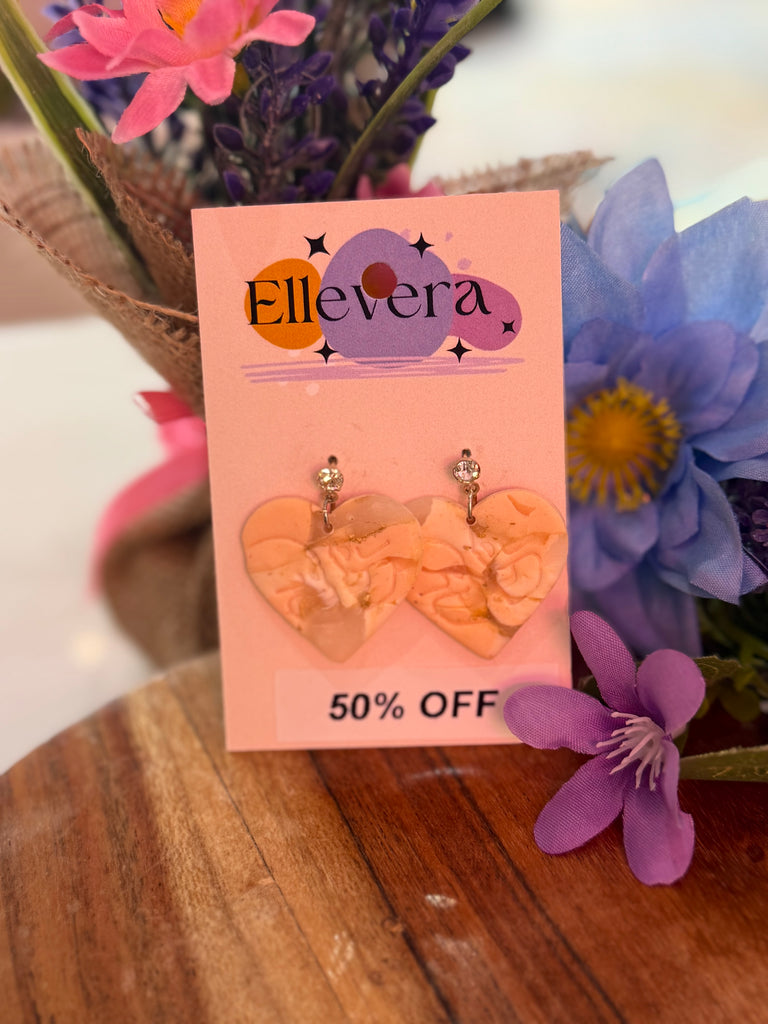 Handmade pink marbled heart-shaped polymer clay earrings with stud tops on Ellevera backing card, marked 50% off.