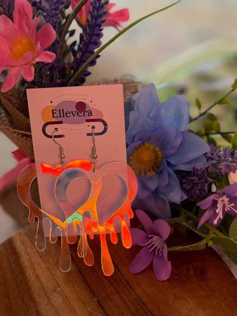 Transparent acrylic dripping heart earrings displayed on Ellevera backing card with floral background.