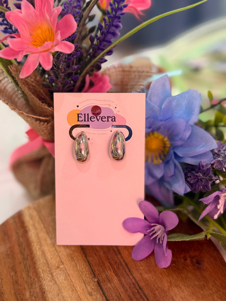 Polished silver chunky huggy earrings displayed on Ellevera backing card with floral background.