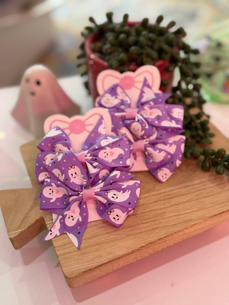 Purple bow hair clips with white ghost print on display card.