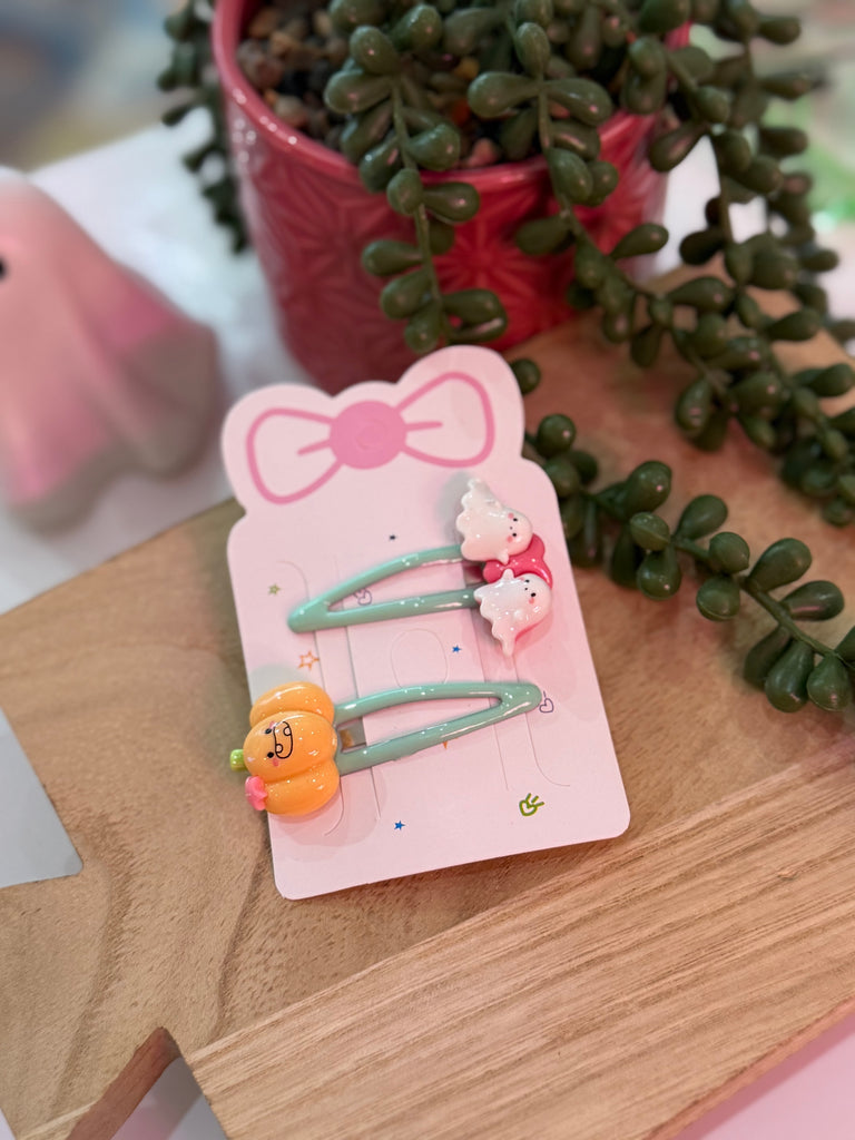 Green snap clip set with pumpkin and ghost decoration on display card.