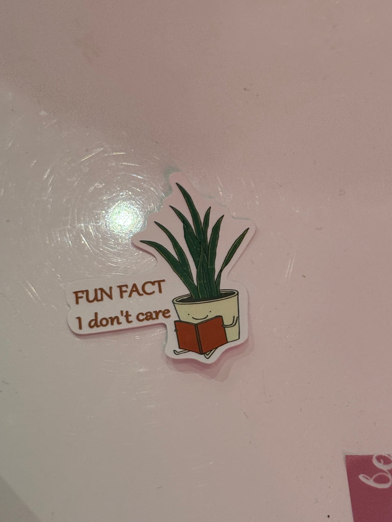Fun Fact I Don’t Care sticker with illustrated plant in a pot holding a book.