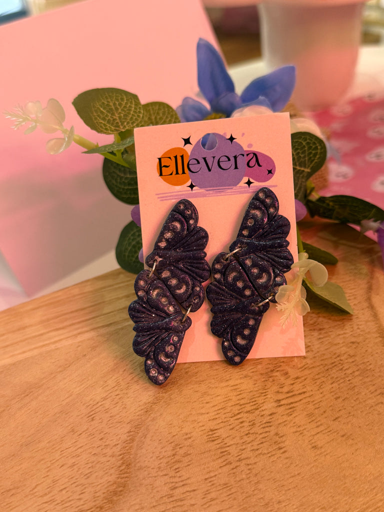 Handmade purple butterfly polymer clay earrings with shimmer detail on Ellevera backing card.