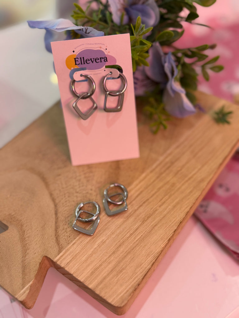 Silver geometric double hoop earrings with linked circle and square design displayed on Ellevera card.