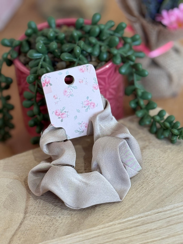 Champagne satin scrunchie displayed on floral backing card.