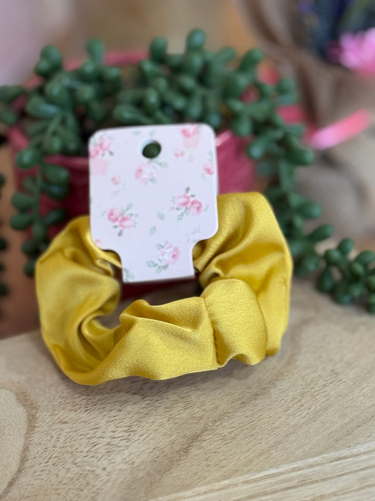 Mustard yellow satin scrunchie on floral backing card.