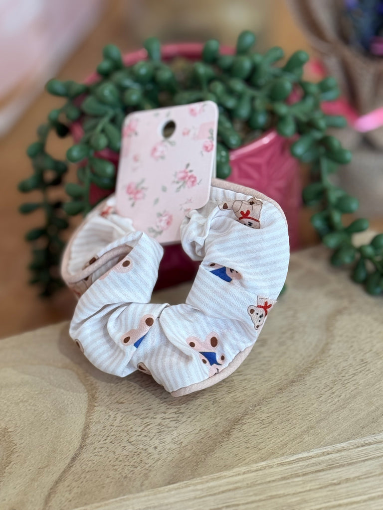 White striped scrunchie with teddy bear print displayed on floral backing card.