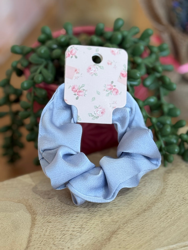 Powder blue satin scrunchie displayed on a floral card.