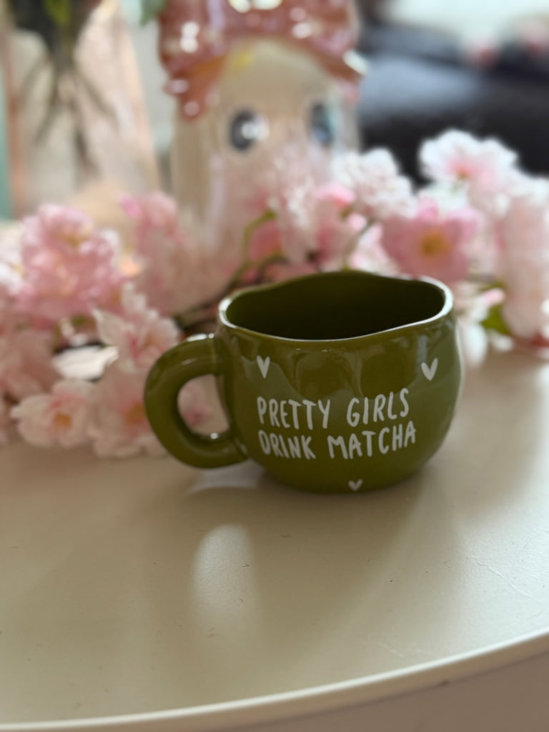 Green ceramic mug with the words "Pretty Girls Drink Matcha."