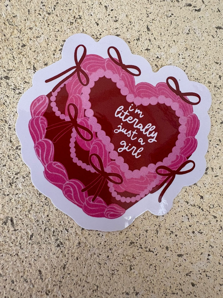 Pink ribbon heart cake style sticker with text “I’m literally just a girl.”